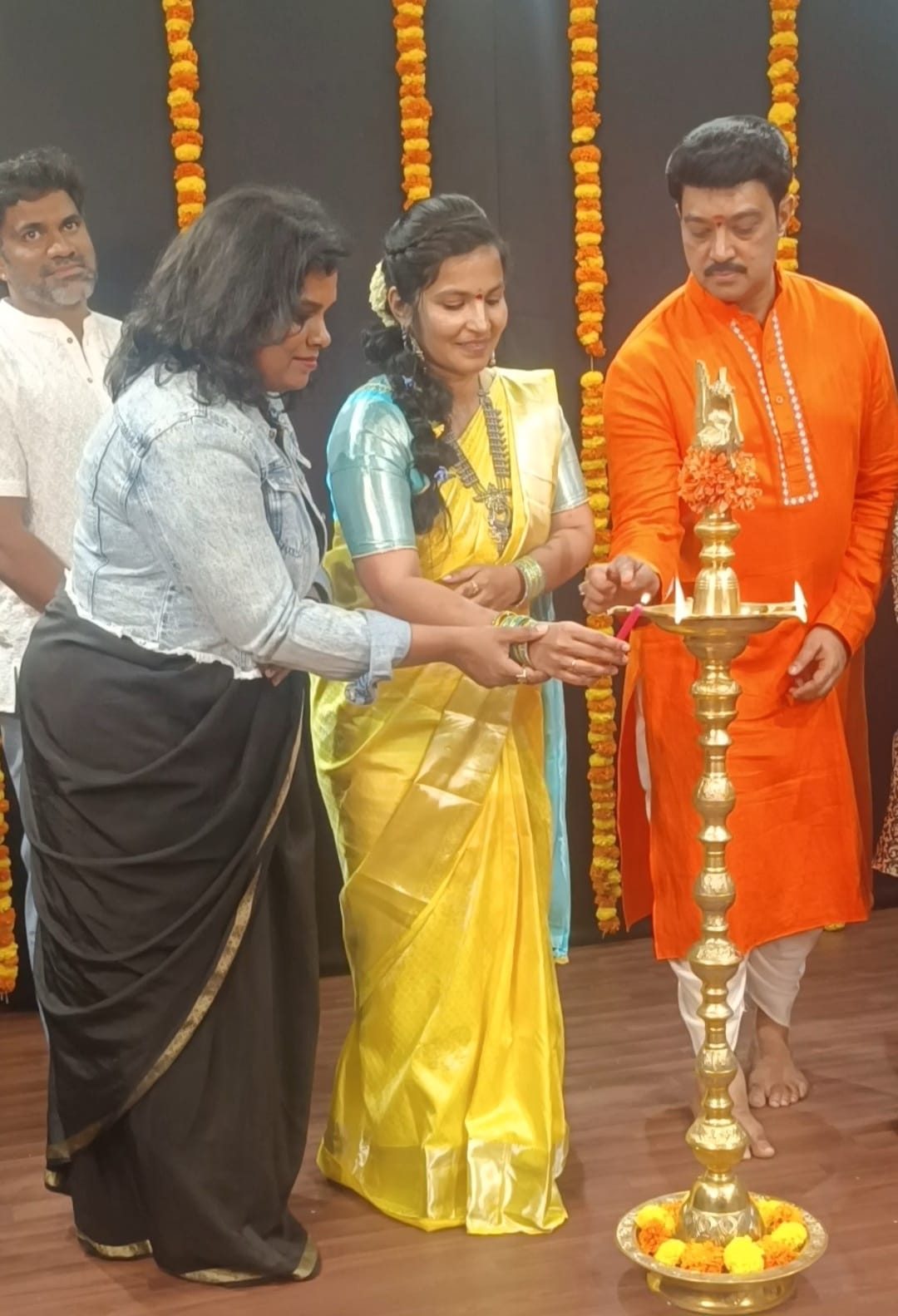 Lighting a tall brass lamp at the opening of a programme