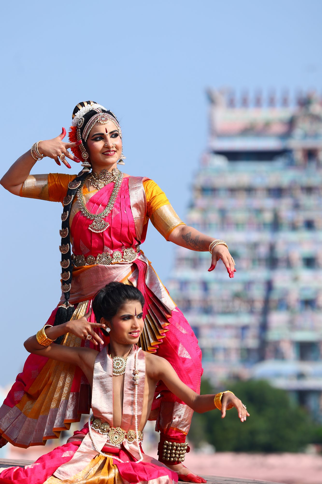 Smt. Pooja Raj dancing with a young student before a South Indian temple gopuram