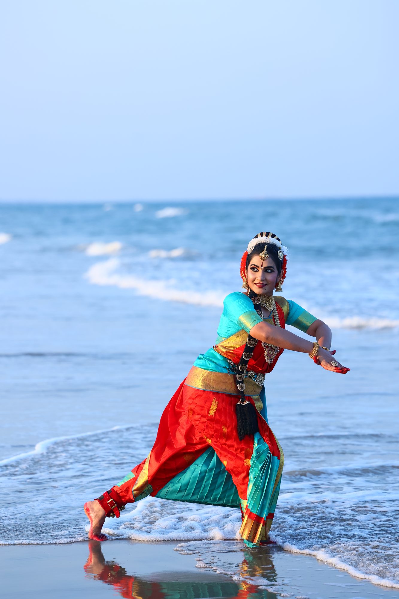Smt. Pooja Raj mid-movement at the shoreline, arms raised
